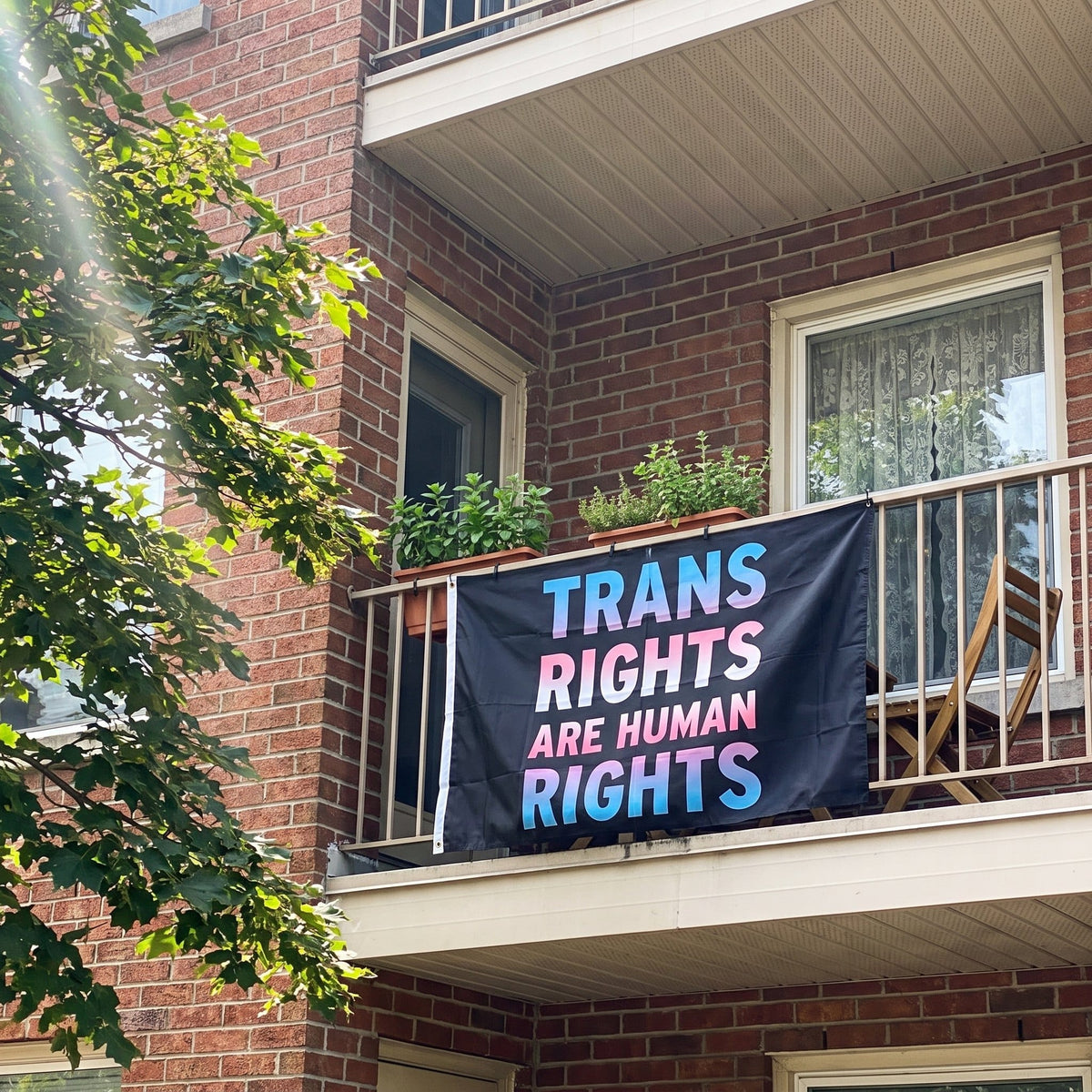 Trans Rights are Human Rights Flag hung over an apartment balcony railing