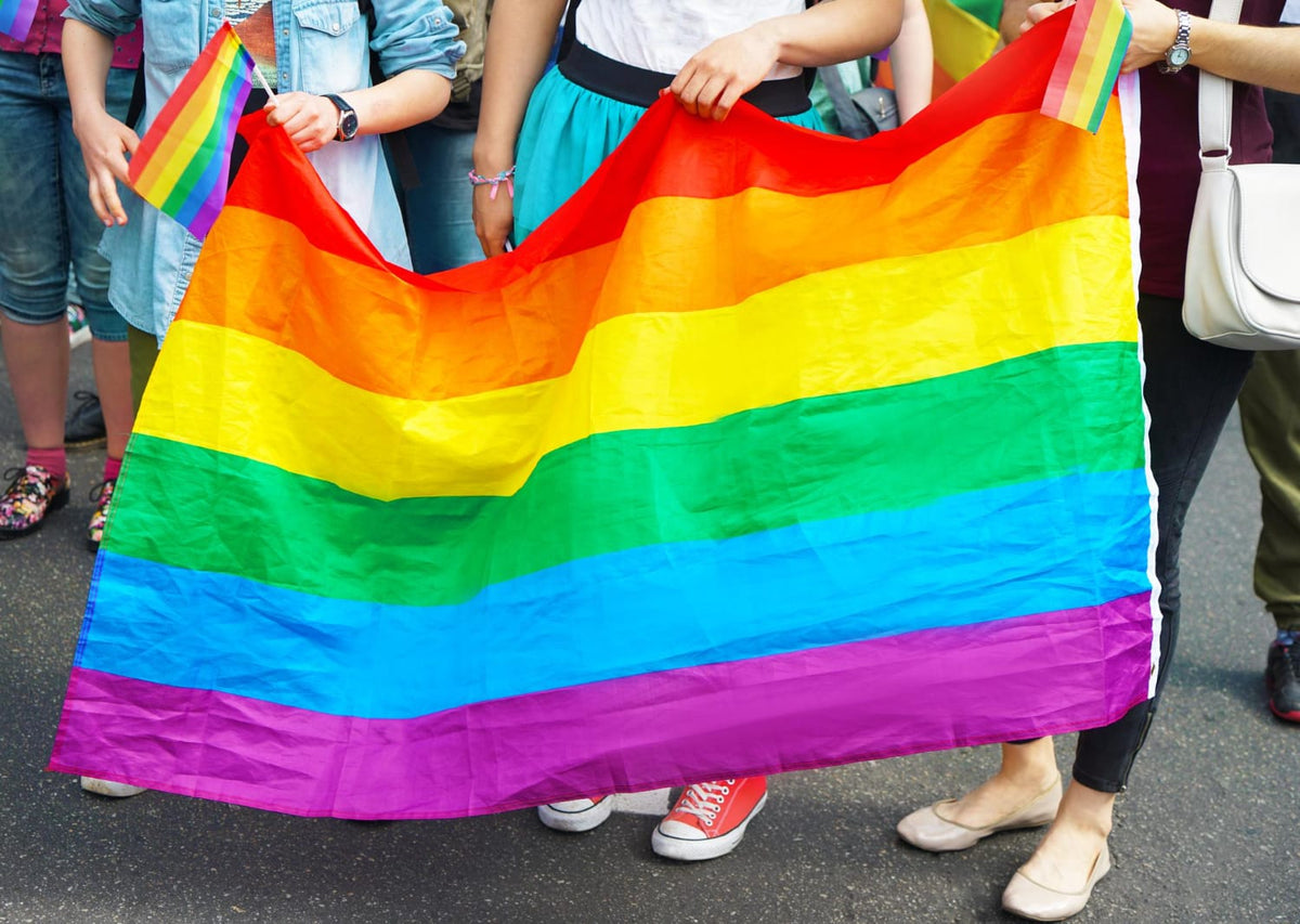 Rainbow pride flag waving above a parade crowd