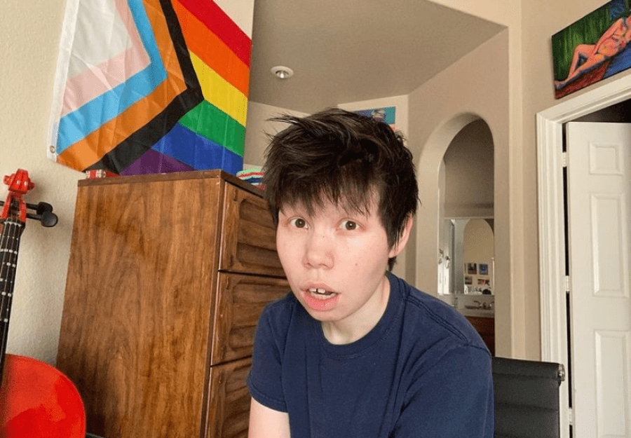 Customer with the Progress Pride Flag hanging on the wall behind them at home